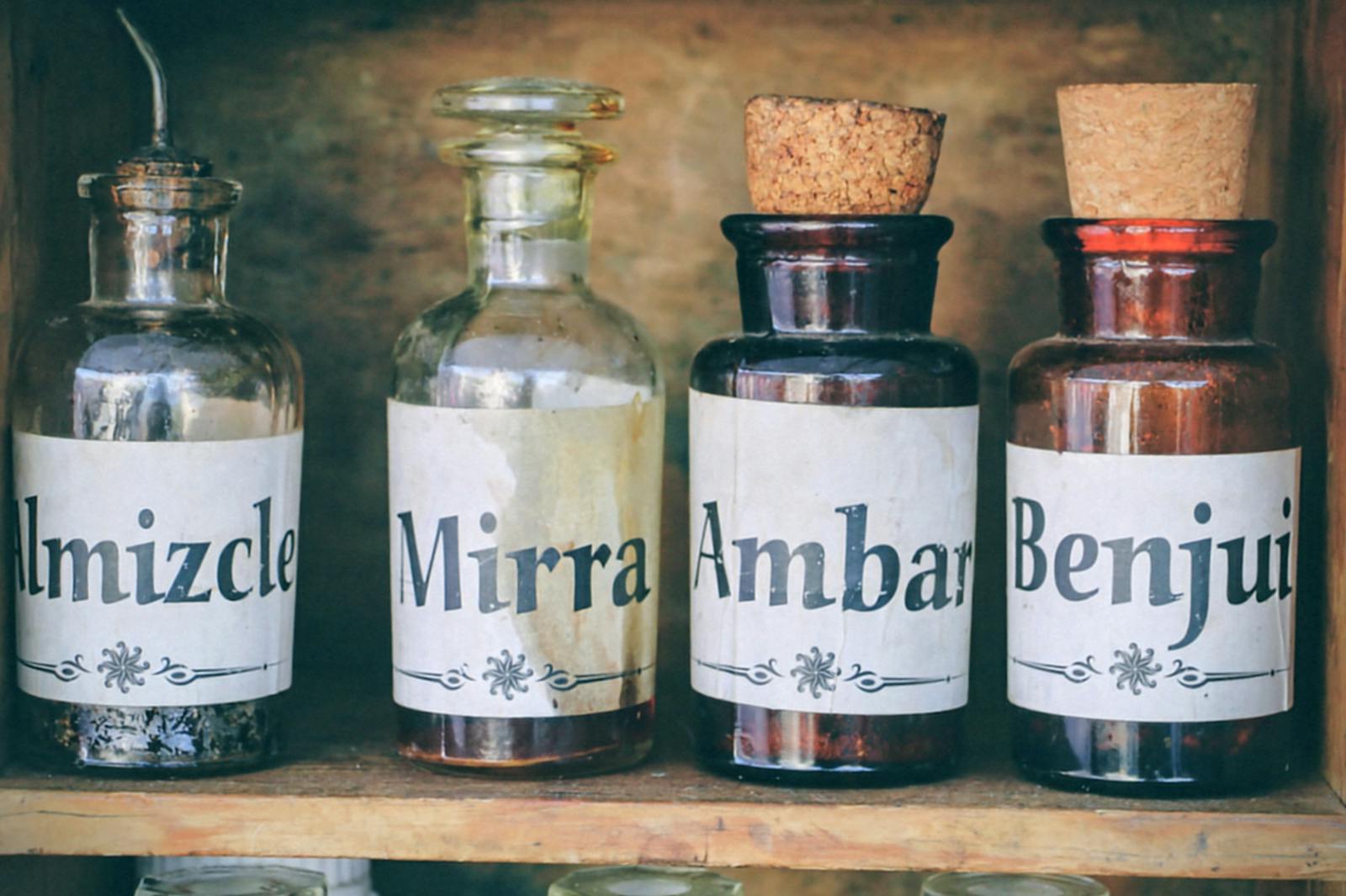 Encens de myrrhe - A collection of vintage apothecary bottles with labels 'Almizcle', 'Mirra', 'Ambar', and 'Benjui'.